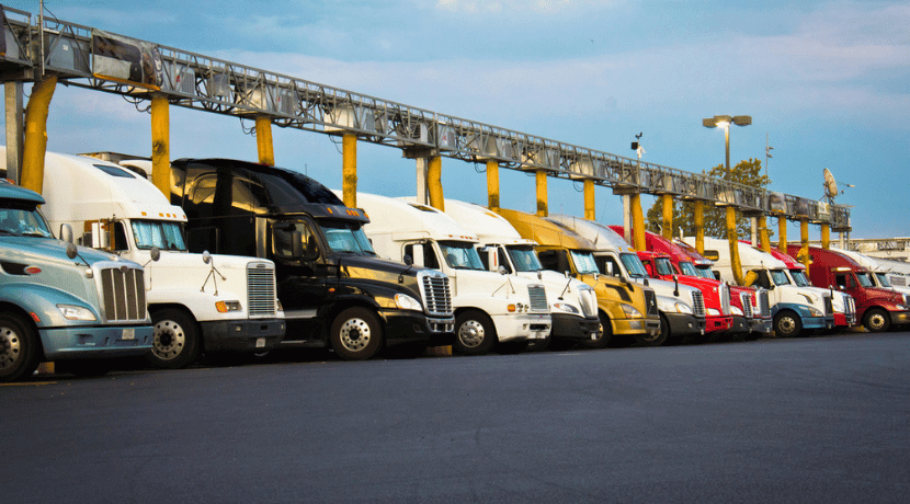 Several Class 8 trucks parked near a truckstop.