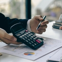 An image of a calculator above paper showing graphs and charts. Used to represent a factoring concept.